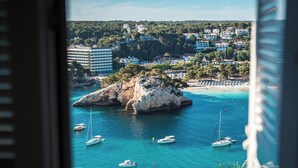A coastal town with clear blue waters, boats, and a rocky outcrop. - Plaça de sa Punta, 4, 07750 Cala Galdana, Balearic Islands, Spanyolország (Cala Galdana)
