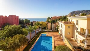 Un espace piscine offrant une vue sur la mer, entouré de bâtiments et de verdure.