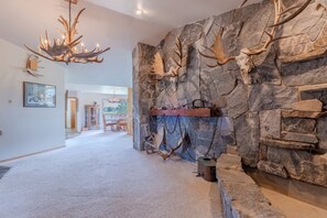 Une pièce dont un mur est recouvert de pierres et orné de bois de cerf et d’un crâne de cerf empaillé.