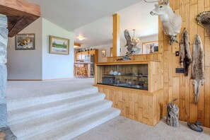 A staircase leading to a wooden-paneled room with mounted animal heads and a display case. - Otter Lodge (West Yellowstone)