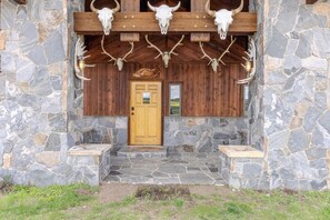 Un bâtiment en pierre avec une porte en bois et un porche orné de bois de cerf.