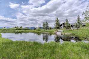 A serene lakeside property with a wooden cabin, a stone bridge, and a well-maintained lawn. - Otter Lodge (West Yellowstone)