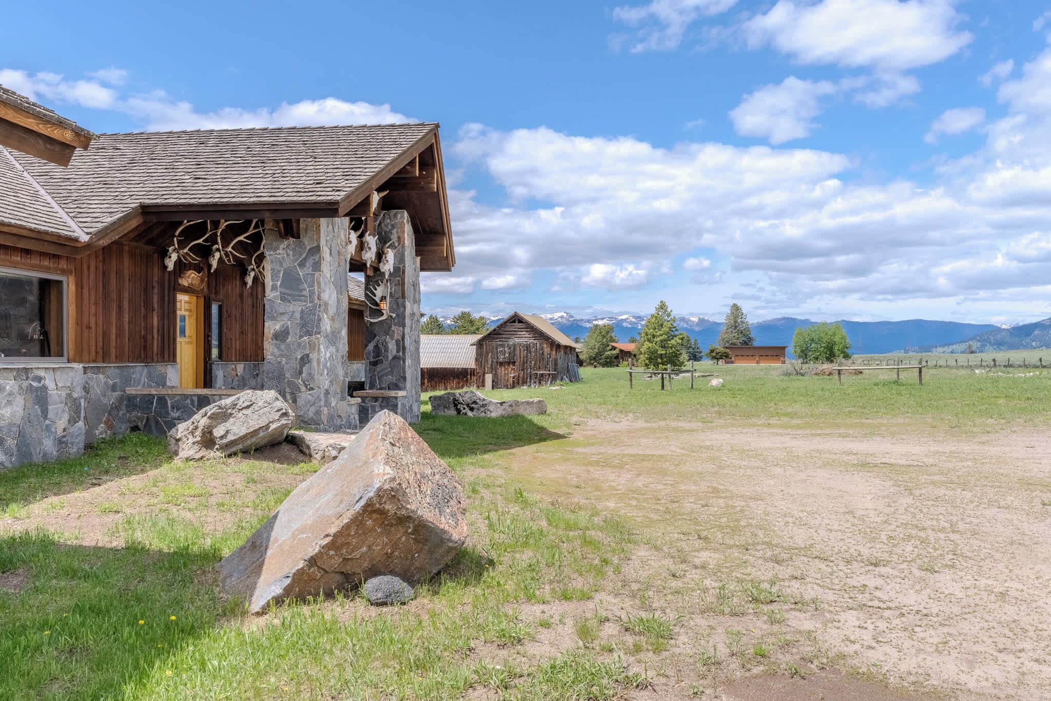Eine rustikale Holzhütte mit Steinunterbau und einem großen Felsen im Vordergrund.