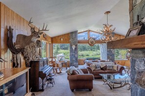 A rustic interior with a fireplace, wooden walls, and deer antlers decor. - Otter Lodge (West Yellowstone)