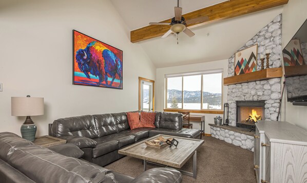 A living room with a leather sofa, a coffee table, a fireplace, and a painting of a buffalo.
