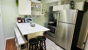 A compact kitchen with a marble countertop, a stainless steel refrigerator, and wooden stools. - Guest suite (Chattanooga)