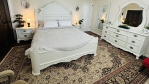 A bedroom with a large bed, a dresser, a nightstand, and a mirror. - Guest suite (Chattanooga)