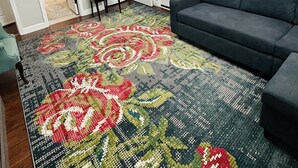 A living room with a dark sofa, a patterned rug, and a painting of a river scene. - Guest suite (Chattanooga)