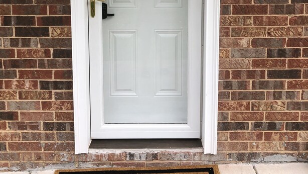 A white door with a doormat that reads "Home" in front of a brick wall. - Guest suite (Chattanooga)