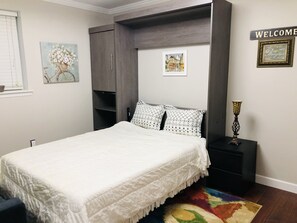 A bedroom with a bed, a nightstand, a dresser, and a colorful rug. - Guest suite (Chattanooga)