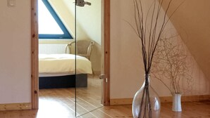 A bedroom with a bed, a glass door, a vase with branches, and a radiator. - Cozy apartment in Börgerende-Rethwisch (Börgerende-Rethwisch)