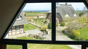 A view from a window overlooking a rural area with traditional houses, a stone pathway, and a grassy field. - Cozy apartment in Börgerende-Rethwisch (Börgerende-Rethwisch)