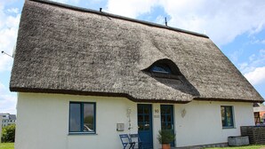 A thatched-roof cottage with a small porch, a blue door, and a number '90' on the wall. - Cozy apartment in Börgerende-Rethwisch (Börgerende-Rethwisch)