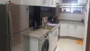 Una cocina compacta con refrigerador, lavadora y una pequeña encimera.
