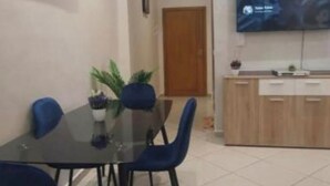 Un comedor con mesa y sillas, una planta en maceta y un televisor en la pared.