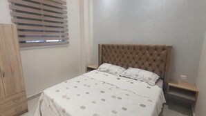 Un dormitorio con cama, armario y ventana con persianas.