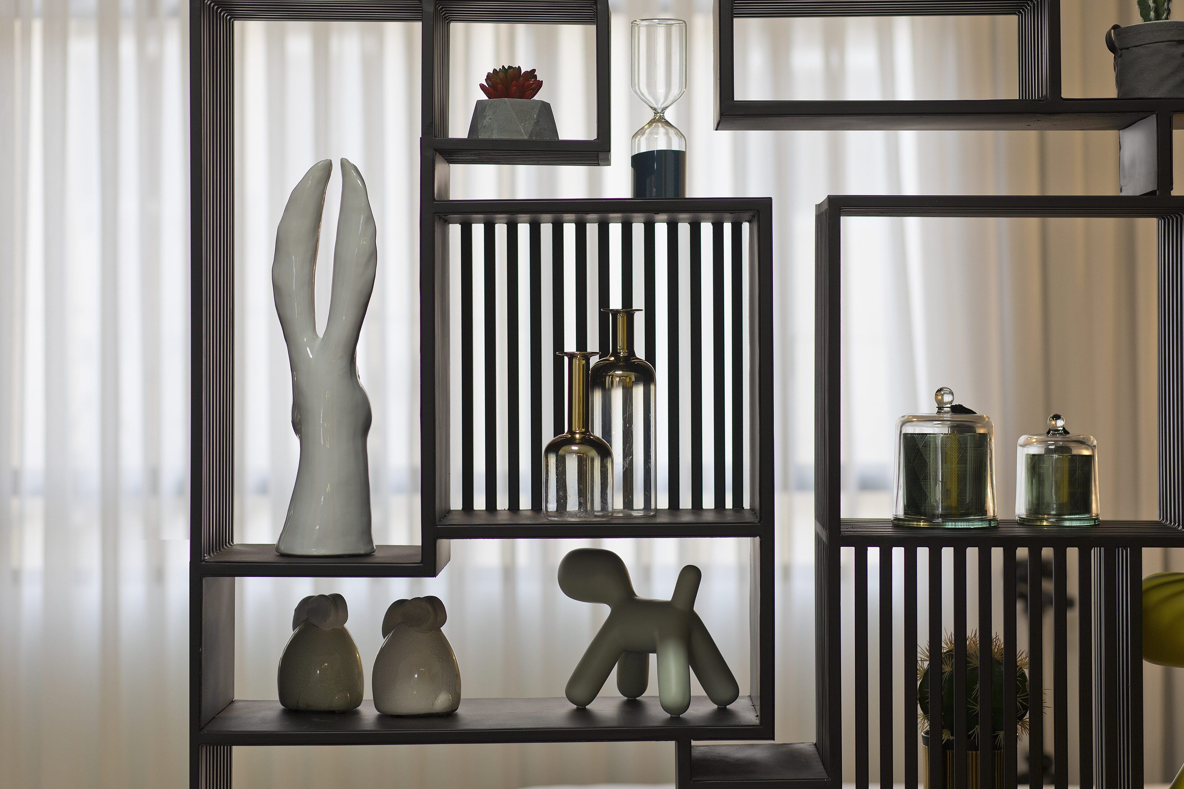 Un interno moderno con scaffali in metallo nero che espongono diversi oggetti decorativi.