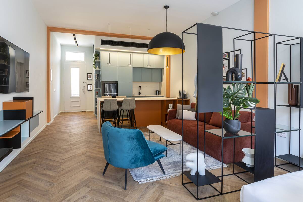 A modern living room with a blue chair, a red sofa, and a black pendant light.