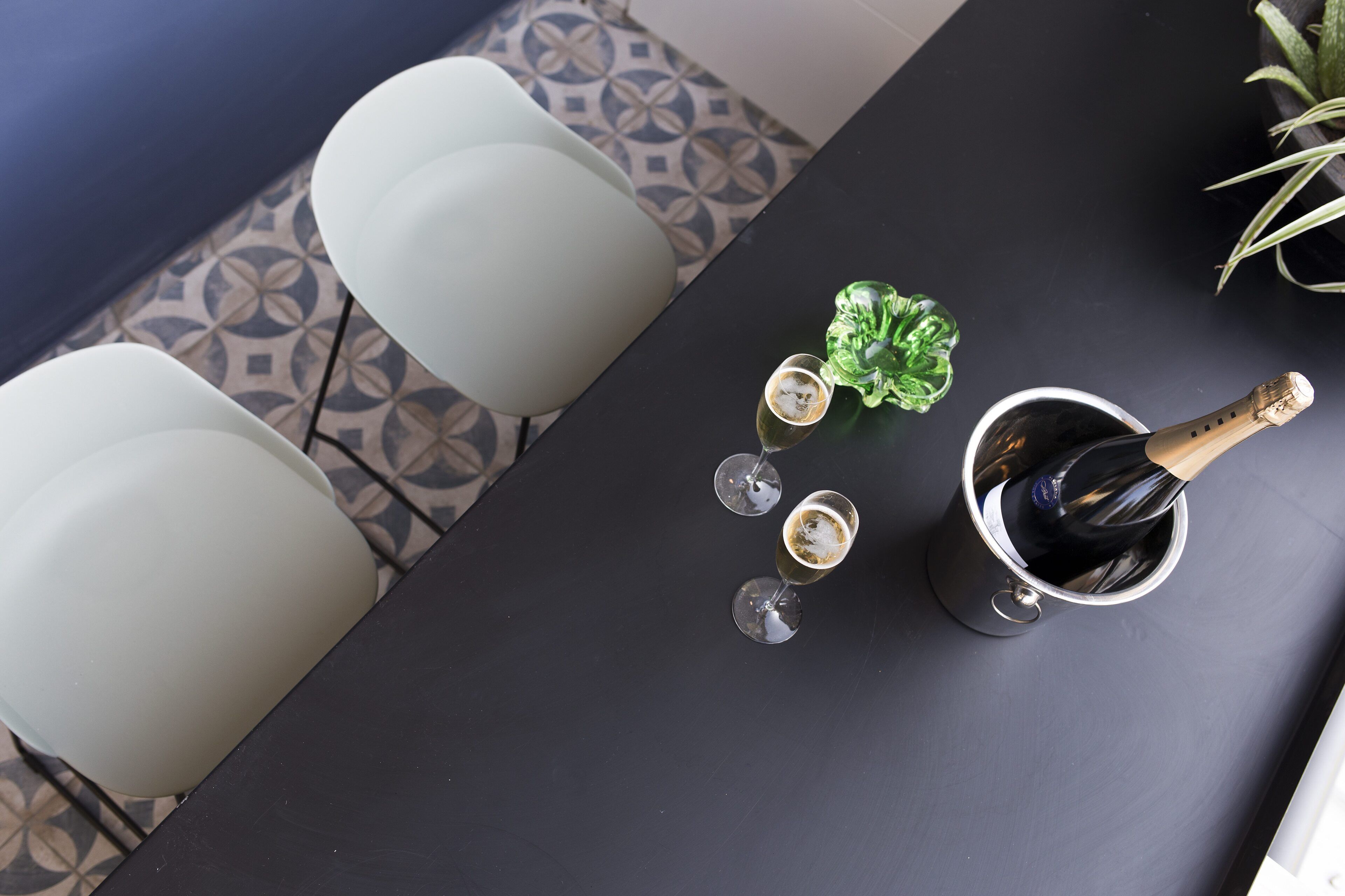 A table with a bottle of champagne, two glasses, and a small decorative item.