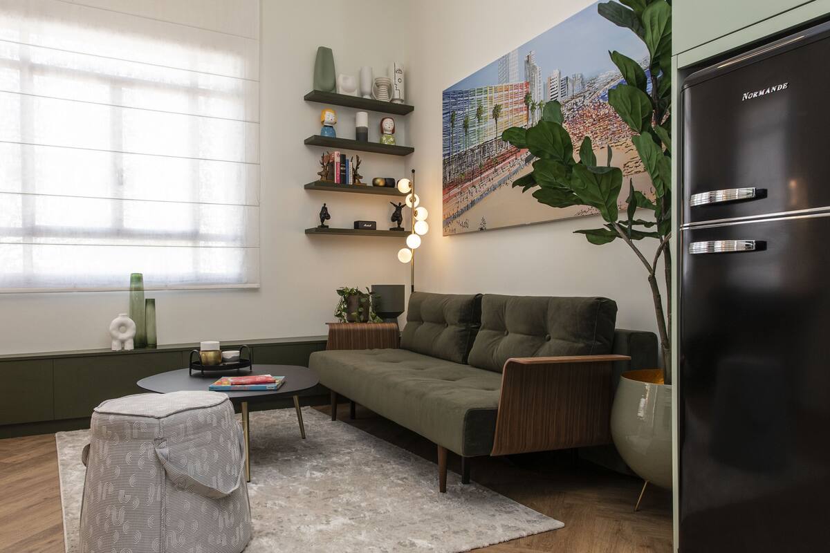 A modern living room with a sofa, a coffee table, a side table with a lamp, a bookshelf, and a large painting on the wall.