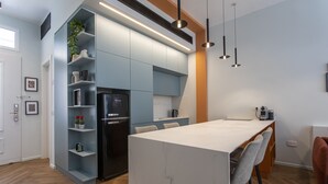 Een moderne keuken met een marmeren eiland, geïntegreerde apparatuur en hanglampen.