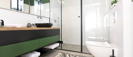 A modern bathroom with a glass shower enclosure, a white sink, and a green vanity.