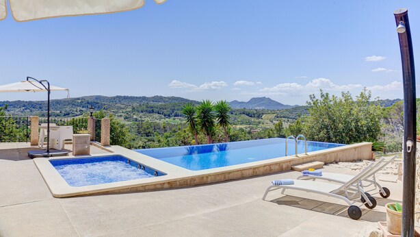 Una piscina a sfioro all'aperto con vista su montagne e vegetazione.
