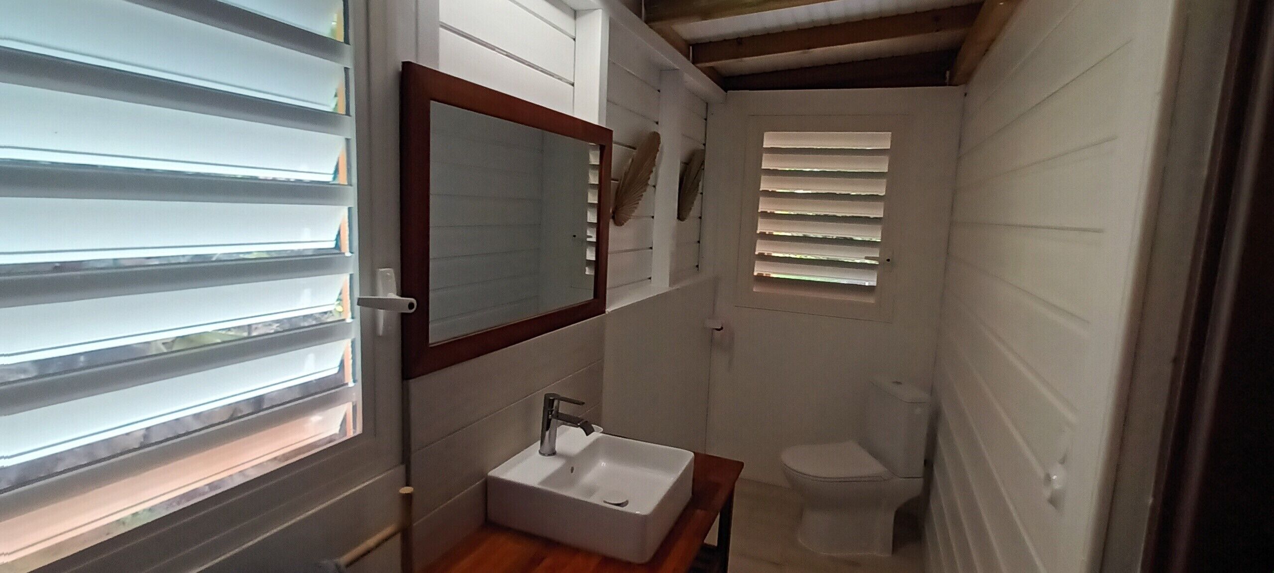 Un baño pequeño y funcional con un lavamanos blanco, un espejo y un inodoro.