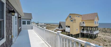 A beachfront property with a covered walkway and multiple buildings, including a house with a balcony and a pier extending into the water.