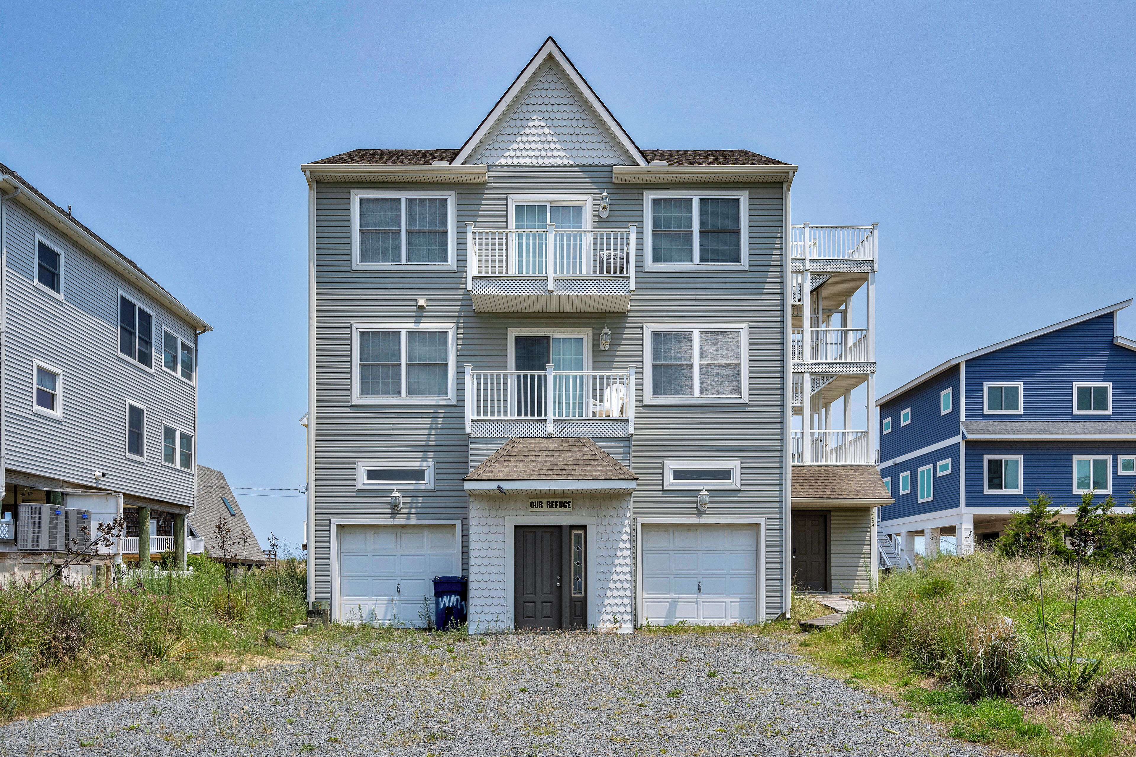 A multi-story residential building with a central entrance, two balconies, and a garage.