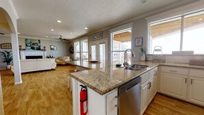 A spacious kitchen with granite countertops, white cabinetry, and a built-in dishwasher.