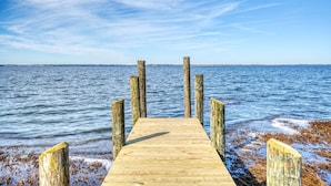 Un muelle de madera que se adentra en un cuerpo de agua, bajo un cielo despejado.