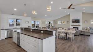 Una cocina amplia con una isla central, armarios blancos y una zona de comedor con mesa y sillas.