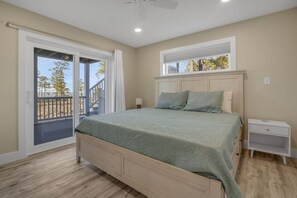 Ein Schlafzimmer mit Bett, Nachttisch und Blick auf einen Balkon.