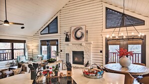 Una cocina amplia con una isla central, una chimenea de piedra y ventanas grandes.