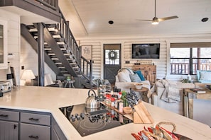 A modern kitchen with a central island, built-in appliances, and a staircase leading to an upper level.