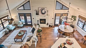 Un salón amplio con chimenea, pisos de madera y ventanas grandes.