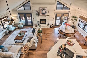 Amplia sala de estar con chimenea, pisos de madera y comedor con una mesa redonda y sillas.