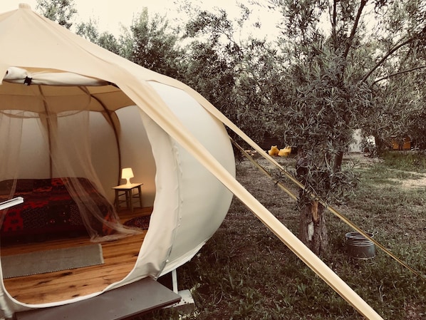 A tent with a bed and a small table with a lamp inside. - Kozluyali Glamping (Ayvacik)