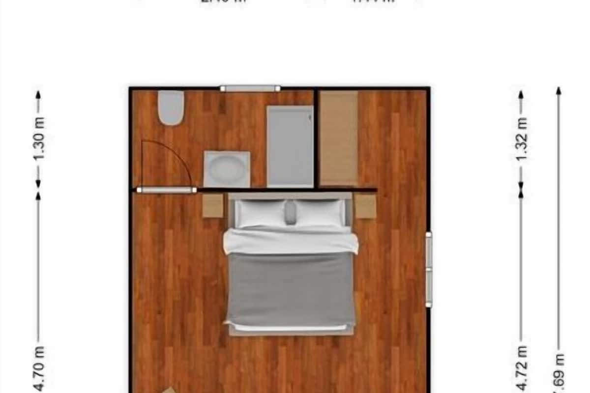 A floor plan of a hotel room with a bed, a small desk, a chair, a sofa, and a bathroom.