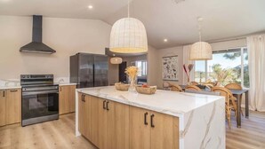 A modern kitchen with a large island, stainless steel appliances, and pendant lighting. - @Marbella Lane -  Charming Tranquil Hideaway (Yucca Valley)