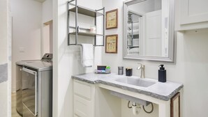 A modern bathroom with a built-in washing machine, a large mirror, and a granite countertop. - Relaxing Lubbock Studio ~ 6 Mi to Texas Tech (Lubbock)