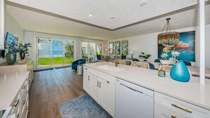 Una cocina amplia con una isla grande, una zona de comedor con sillas y vistas al exterior.