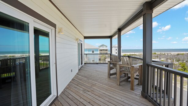 A wooden deck with a railing, a table, and two chairs. - Fond Horizons: Beach View, Private Pool, Pet Friendly! (Cape San Blas)