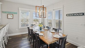 A dining area with a wooden table set for six, surrounded by chairs, with a hanging light fixture above. - Fond Horizons: Beach View, Private Pool, Pet Friendly! (Cape San Blas)