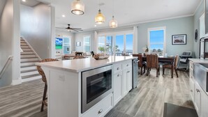 Una cocina amplia con una isla central, iluminación colgante y vistas al exterior.