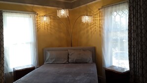 A bedroom with a bed, two bedside tables, and three wall-mounted lights. - The Cam Grady, Restored, roomy, eclectic cottage in heart of Downtown Morganton (Morganton)