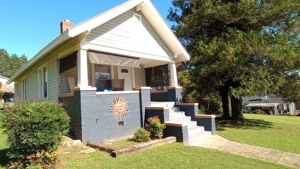 A single-story house with a gabled roof, a front porch, and a brick accent wall. - The Cam Grady, Restored, roomy, eclectic cottage in heart of Downtown Morganton (Morganton)