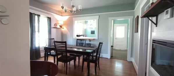 A dining area with a table and chairs, a kitchen area with a stove, and a door leading to another room.