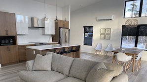 A modern kitchen with wooden cabinets, a central island, and pendant lighting. - Modern three bedroom with Panoramic Oceanview  (Hubbards)